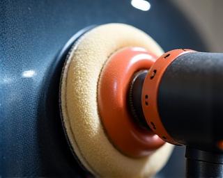 Close-up of a machine polisher working on a car's side panel